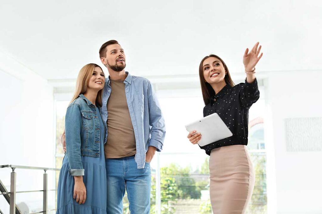 A couple sitting at a table with a real estate agent, discussing documents and asking questions.