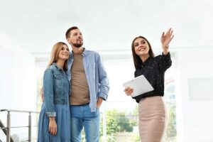 A couple sitting at a table with a real estate agent, discussing documents and asking questions.